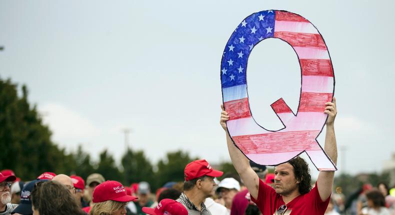 A protester holds a Q sign as he waits in line with others to enter a Trump campaign rally in Wilkes-Barre, Pennsylvania.