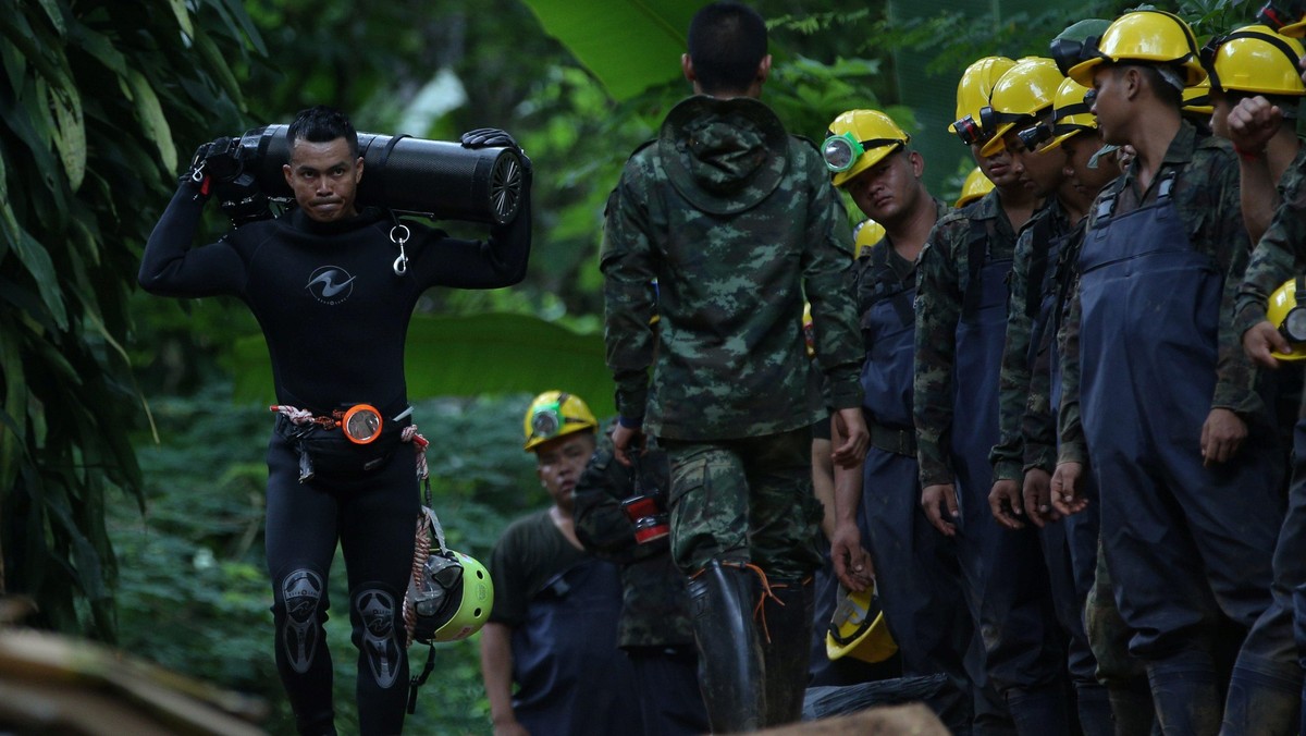 A diver carries an oxygen tank as he leaves the Tham Luang cave complex, where 12 boys and their soc