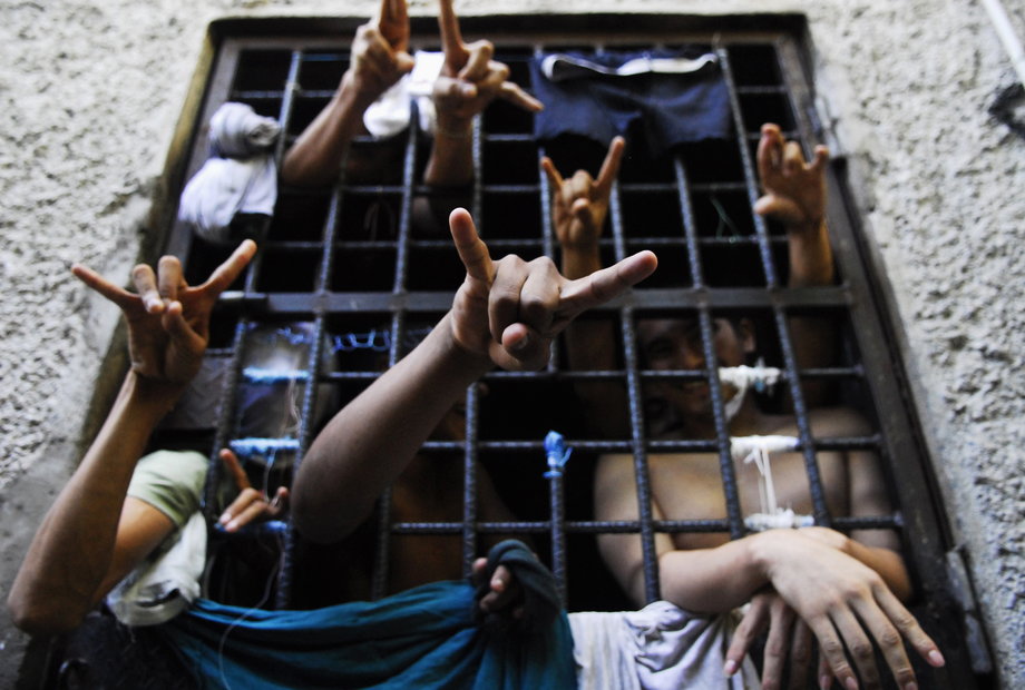 People arrested for being members of the MS-13 Mara Salvatrucha street gang, among other crimes, flash their gang's hand sign from inside a jail cell at a police station in San Salvador, El Salvador, October 12, 2012.