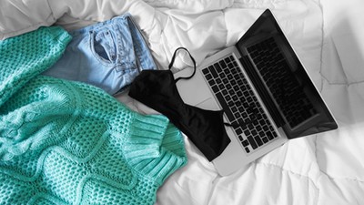 Female outfit and laptop laid out on bed, morning light