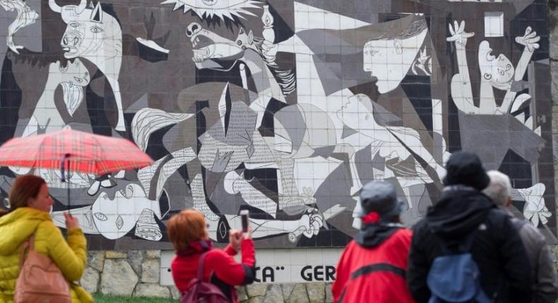 Tourists take pictures of a mural depicting Pablo Picasso's painting Guernica in the northern Spanish town on the 80th aniversary of a Nazi bombing raid that killed hundreds