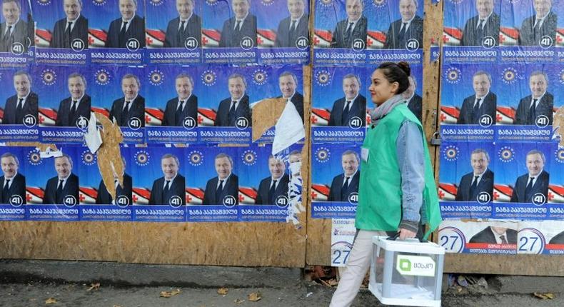 An official carries a ballot box past election posters during the parliamentary polls in Tbilisi on October 30, 2016