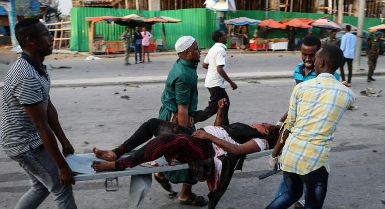 People rescue a wounded person after the triple bomb attack