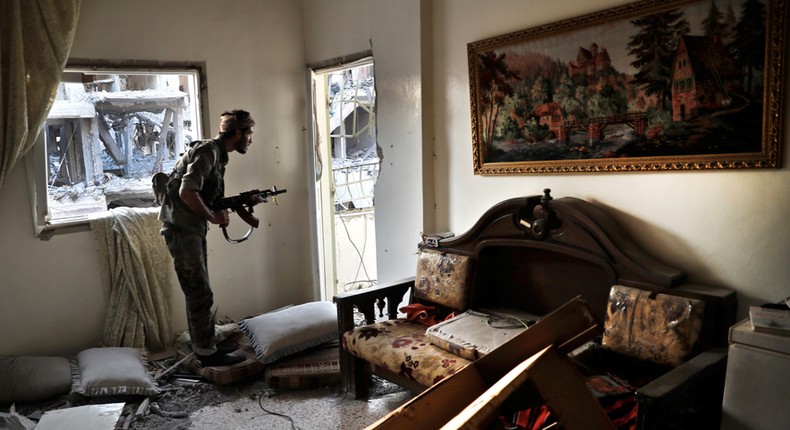 An SDF fighter looks through a window in Raqqa.