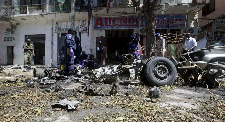 Somali soldiers and explosion experts assess the wreckage of a car destroyed in a bomb explosion at a local government headquarters that killed five people in Somalia's capital Mogadishu, April 11, 2016. REUTERS/Ismail Taxta