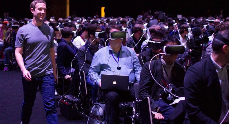 Facebook CEO Mark Zuckerberg (left) walks past a crowd with virtual reality (VR) headsets.
