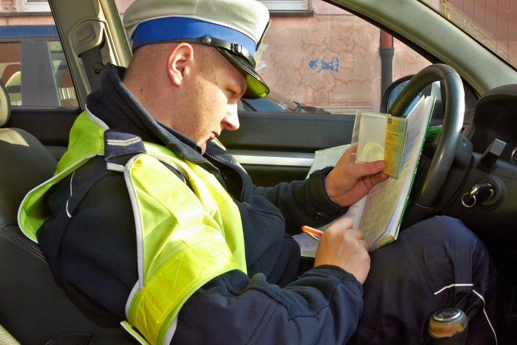 Policjant zatrzymuje dowód rejestracyjny i wypisuje pokwitowanie