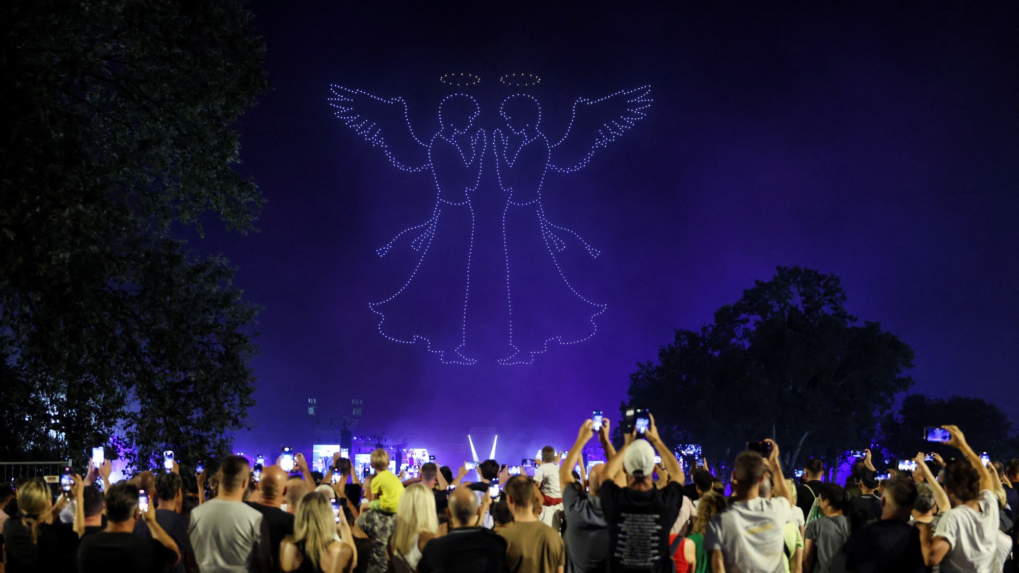 Ľudia sledujú svetelnú šou dronov počas koncertu Marka Perkoviča Thompsona, ktorý sa chystá prekonať svetový rekord za najväčší platený koncert, v chorvátskom Záhrebe, REUTERS/Antonio Bronic