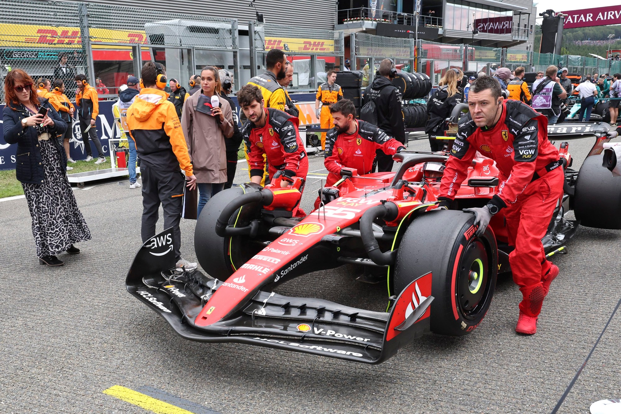 Mechanici presúvajú auto pilota Ferrari Carlosa Sainza.
