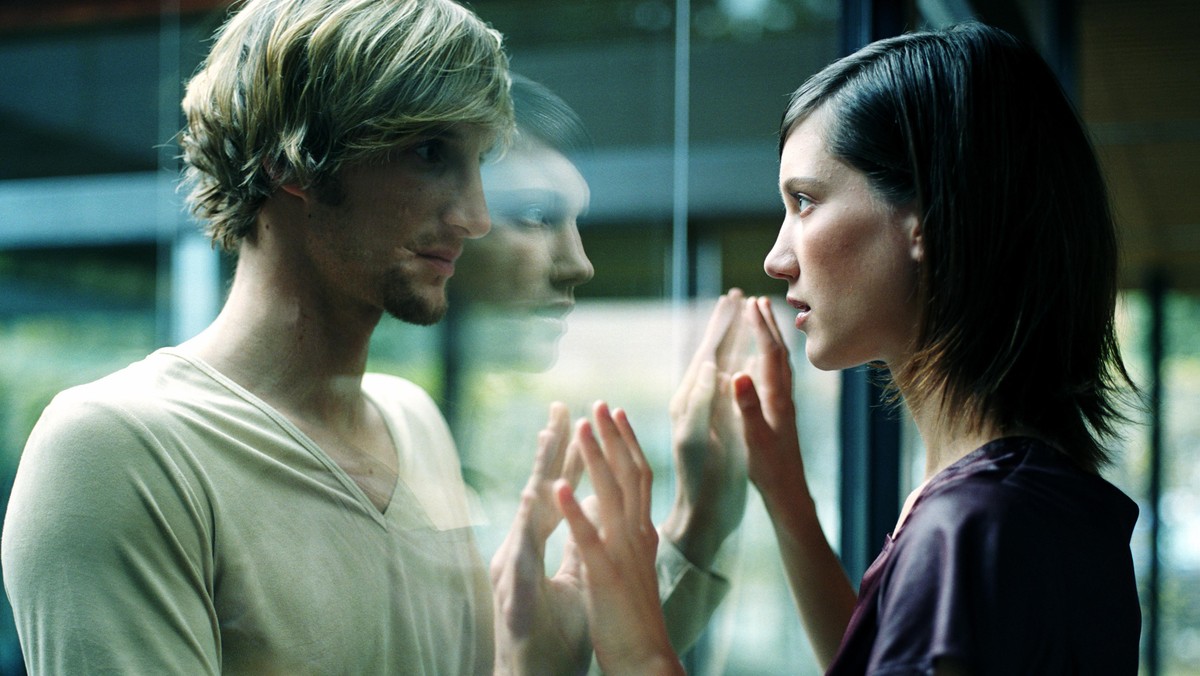 Young couple touching hands through glass, close-up