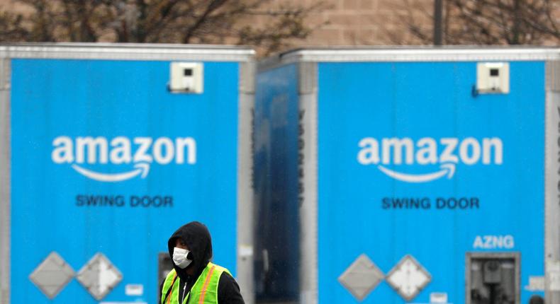 FILE PHOTO: A worker in a face mask walks by trucks parked at an Amazon facility as the global coronavirus outbreak continued in Bethpage on Long Island in New York, U.S., March 17, 2020. REUTERS/Andrew Kelly/File Photo