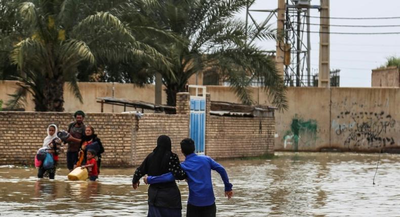 An Iranian family walks through a flooded street in a village around the city of Ahvaz