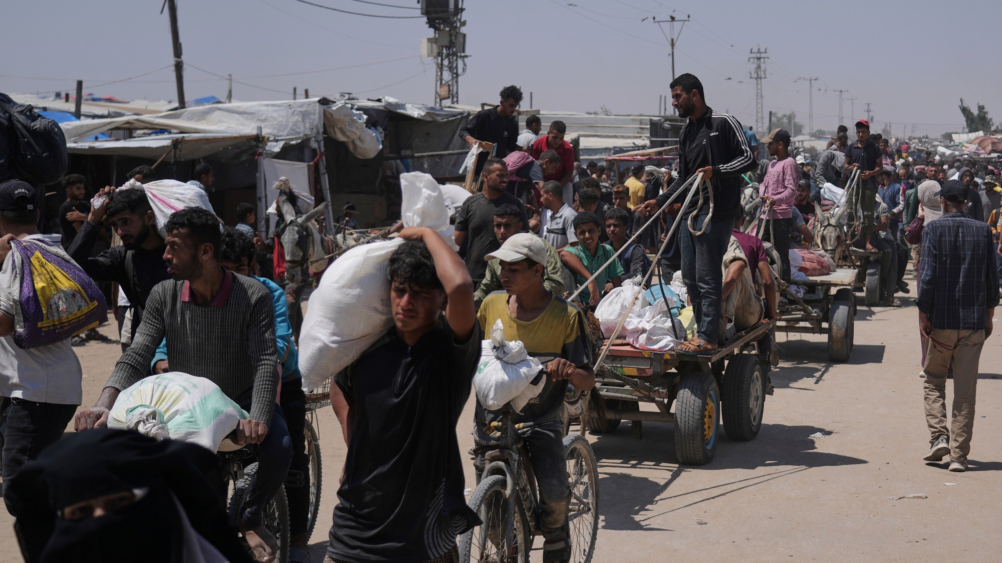 Palestínčania nesú vrecia s potravinami a balíčkami humanitárnej pomoci, ktoré dodala Humanitárna nadácia pre Gazu, organizácia podporovaná USA, v Rafahu na juhu pásma Gazy.