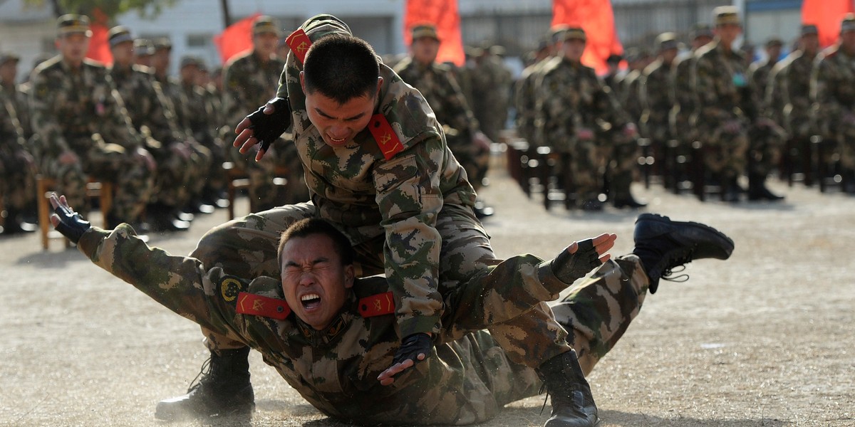 Paramilitary policemen take part in an unarmed combat demonstration for the new recruits (background) at a military base in Hefei, Anhui province, China.