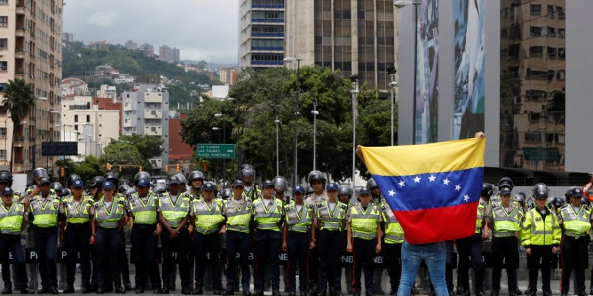 An opposition supporter stands with the Venezuelan flag in front of police during a rally to demand a referendum to remove President Nicolas Maduro in Caracas.