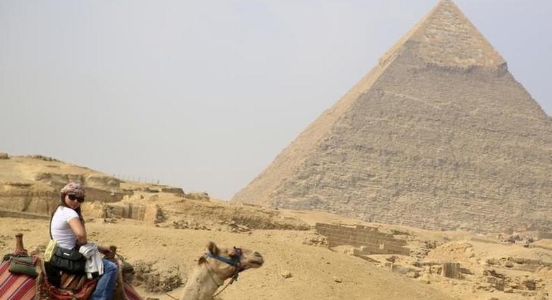 A British tourist rides a camel in front of the Giza pyramids on the outskirts of Cairo, Egypt, November 8, 2015. REUTERS/Amr Abdallah Dalsh