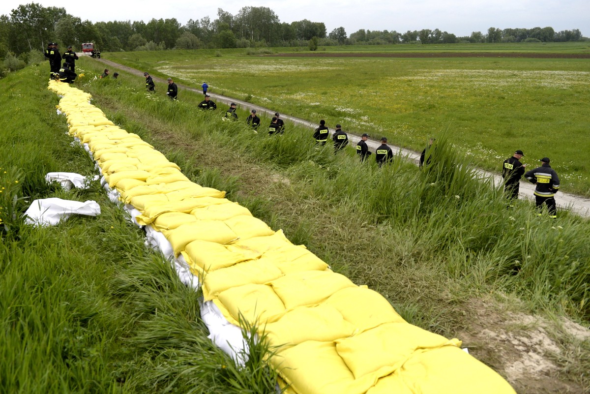 Strażacy układają worki z piaskiem na wale przeciwpowodziowym