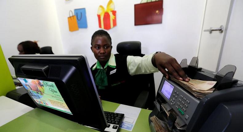 An employee uses a money counting machine as she serves a customer inside a mobile phone care centre operated by Kenyan's telecom operator Safaricom; in the central business district of Kenya's capital Nairobi, May 11, 2016. 