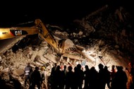 Rescuers work in the night at a collapsed house following an earthquake in Pescara del Tronto