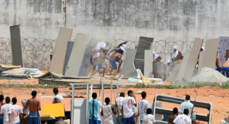 Prisoners use makeshift shields as riot police fire rubber bullets during a rebellion at the Alcacuz jail near the northeastern city of Natal on January 17, 2017