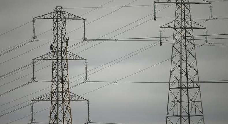 Workers paint an electricity pylon near Lymm, northern England February 18, 2015.   REUTERS/Phil Noble