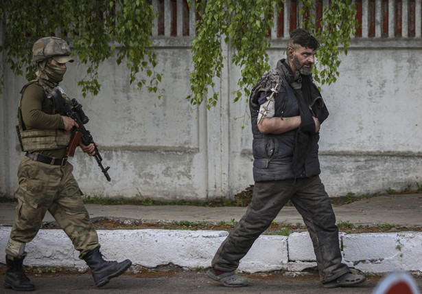 Jeden z obrońców Azowstalu eskortowany przez żołnierza Donieckiej Republiki Ludowej