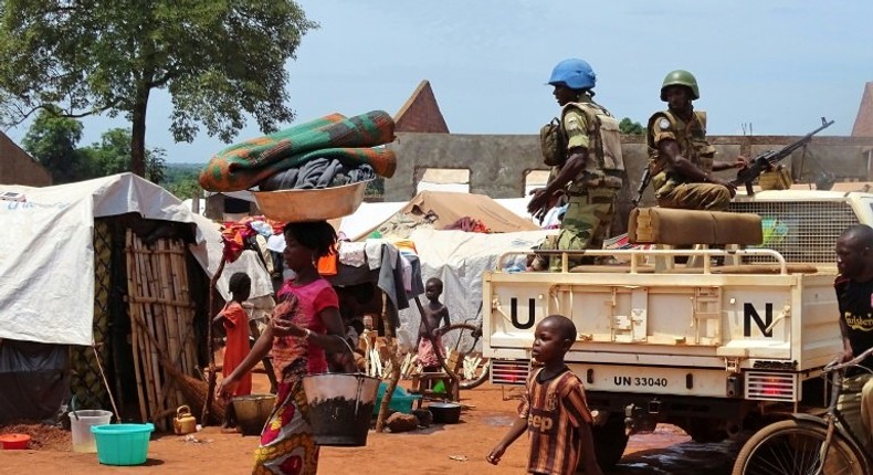 A woman and a child walk past UN peacekeepers from Gabon patrolling the Central African Republic town of Bria on June 12, 2017