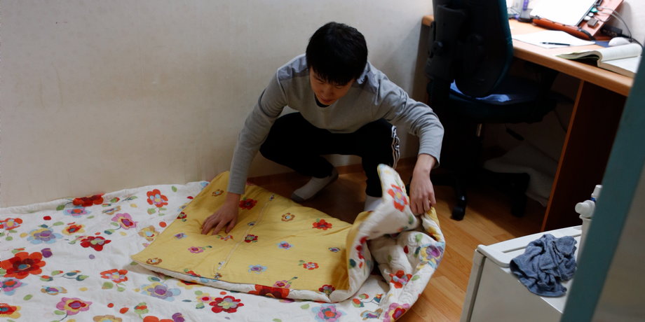 An exam applicant folds a quilt in his small room in one of the many private dorms that house students cramming for exams in a neighborhood of Seoul called Exam Village on December 13, 2012.