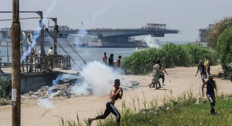 Egyptians run for cover from tear gas during clashes with security forces in the Nile island of Warraq in Giza province, north of the capital Cairo, on July 16, 2017