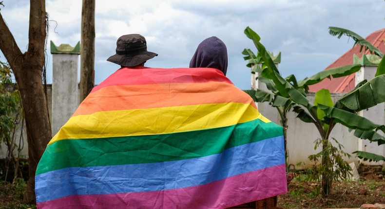 A gay Ugandan couple cover themselves with a pride flag as they pose for a photograph in Uganda Saturday, March 25, 2023.AP Photo