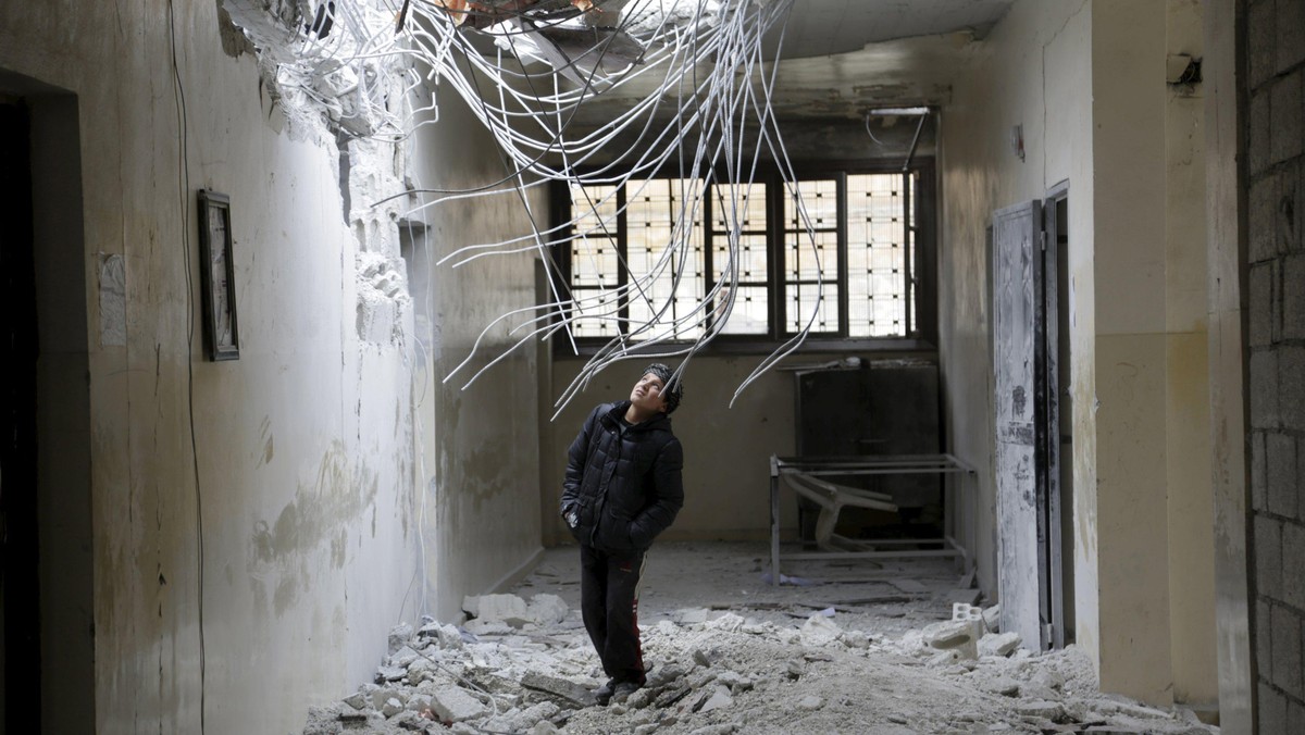 A boy inspects damage inside his school, due to what activists said was an air strike carried out ye