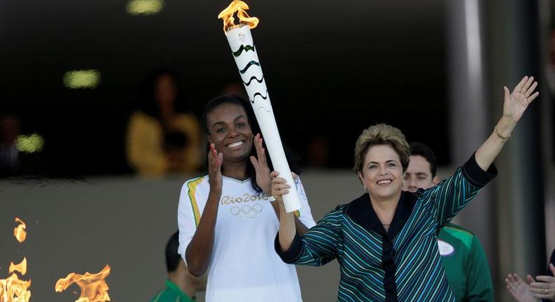 Brazil's President Dilma Rousseff (R) waves after lighting a cauldron with the Olympic Flame next to Fabiana Claudino, captain of the Brazilian volleyball team, during the Olympic Flame torch relay at Planalto Palace in Brasilia, Brazil, May 3, 2016. REUTERS/Ueslei Marcelino