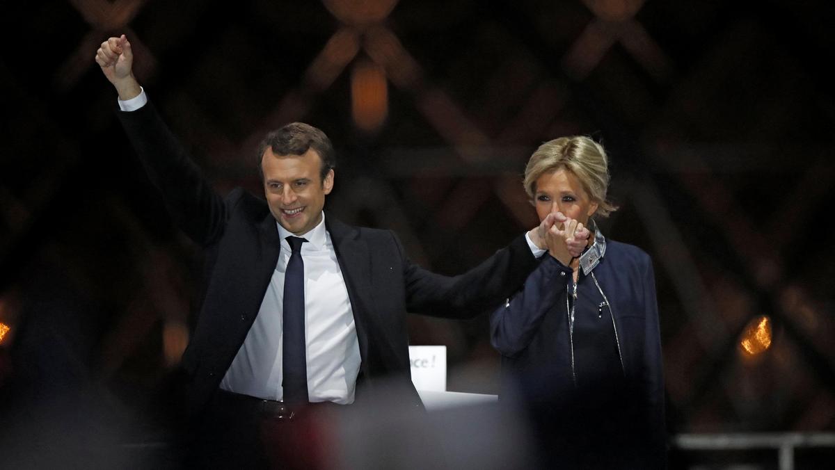 French President elect Emmanuel Macron and his wife Brigitte Trogneux celebrate on the stage at his victory rally near the Louvre in Paris