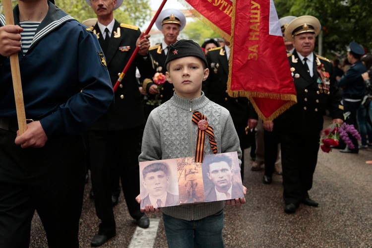 Chłopiec ze zdjęciami krewnych, którzy walczyli w szeregach armii radzieckiej. Dzień Zwycięstwa w Sewastopolu