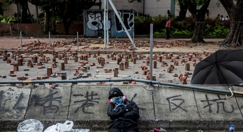 A Hong Kong pro-democracy protester sleeps on a barricaded street outside a university