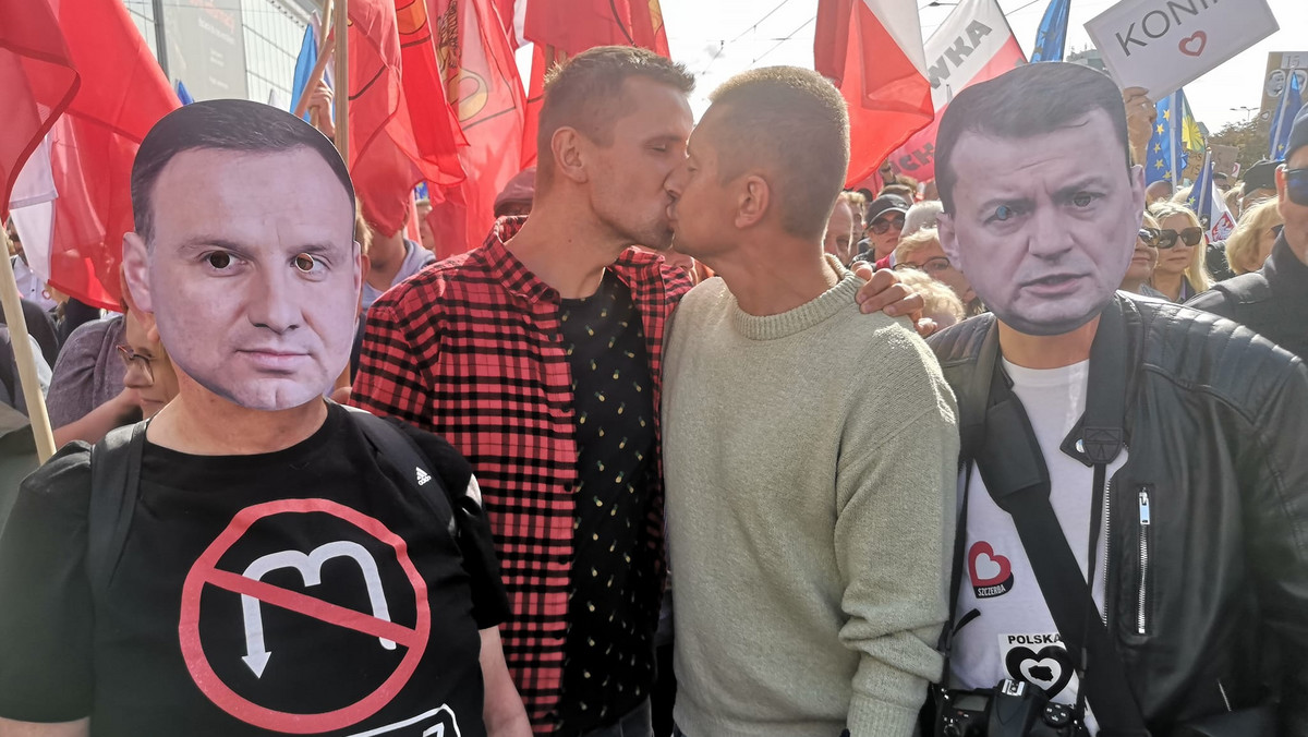 Para gejów całowała się na marszu. Obok stali ludzie w maskach Dudy i Błaszczaka