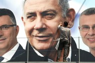 A labourer works on hanging up a Likud election campaign banner depicting Israeli Prime Minister Ben