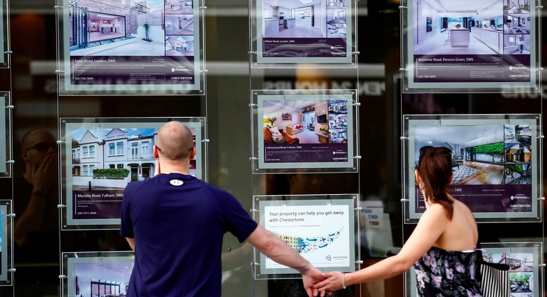 A couple view properties for sale in an estate agents window in London