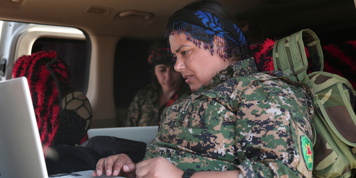 A Kurdish fighter from the People's Protection Units (YPG), operating alongside the Syrian Democratic Forces (SDF), sits inside a vehicle as she works on a laptop in the town of Hisha after the SDF took control of the area from ISIS, in the northern Raqqa countryside, Syria, November 14, 2016.