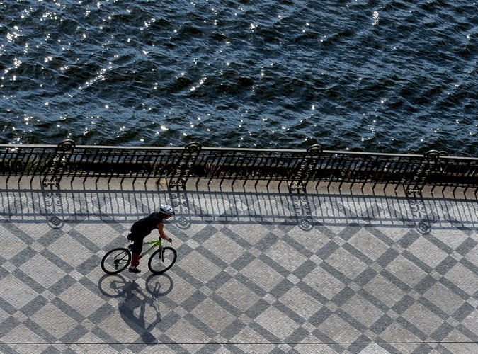 Rowerzysta jadący wzdłuż Wełtawy w Pradze. Temperatury w Czechach przekraczają 30 stopni Celsjusza