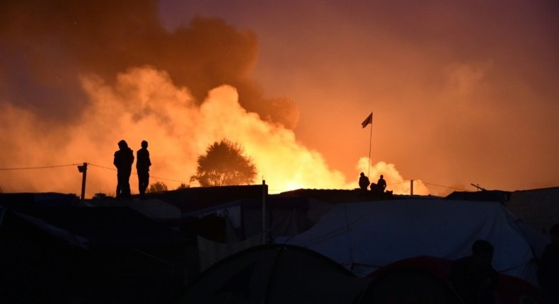 People look at smoke rising during the demolition of the Calais Jungle camp in northern France on October 25, 2016