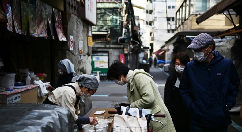 A woman in a face mask buys food from a vendor in Tokyo