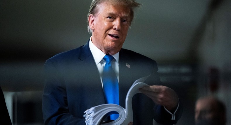 Former US president and Republican presidential candidate Donald Trump holds news clippings as he speaks to the press in the court hallway.JABIN BOTSFORD/POOL/AFP via Getty Images