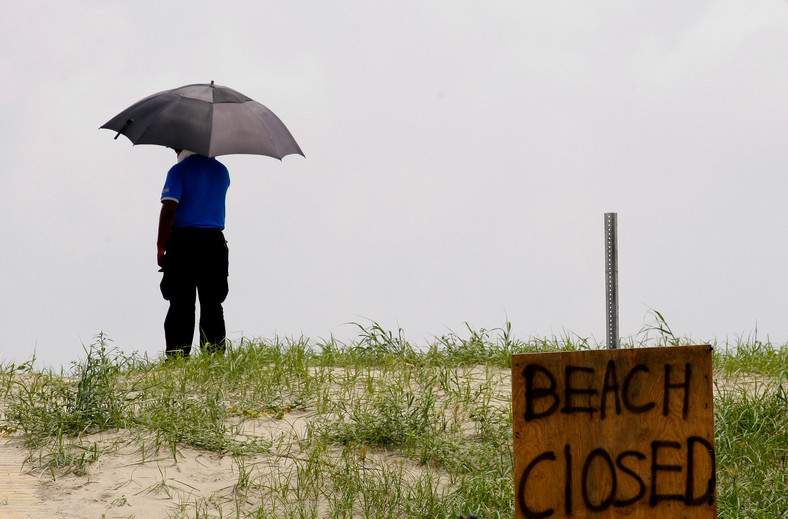 Katastrofa w Zatoce Meksykańskiej: Grand Isle, Louisiana, USA. Człowiek z parasolem na zamknięctej plaży przygląda się zniszczeniom jakich dokonała ropa. Foto: Derick E. Hingle/Bloomberg