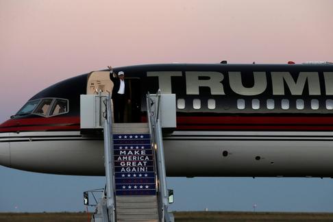 Republican presidential nominee Donald Trump waves as he walks off his plane at a campaign rally in 