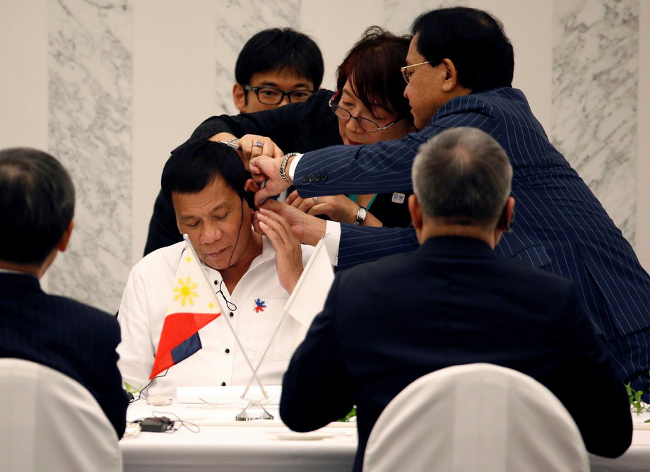 Philippine President Rodrigo Duterte is helped by interpreters to attach an earphone as he attends a luncheon meeting with Japanese business leaders in Tokyo, Japan, October 26, 2016.