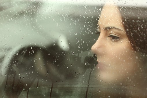 Sad woman looking through a car window