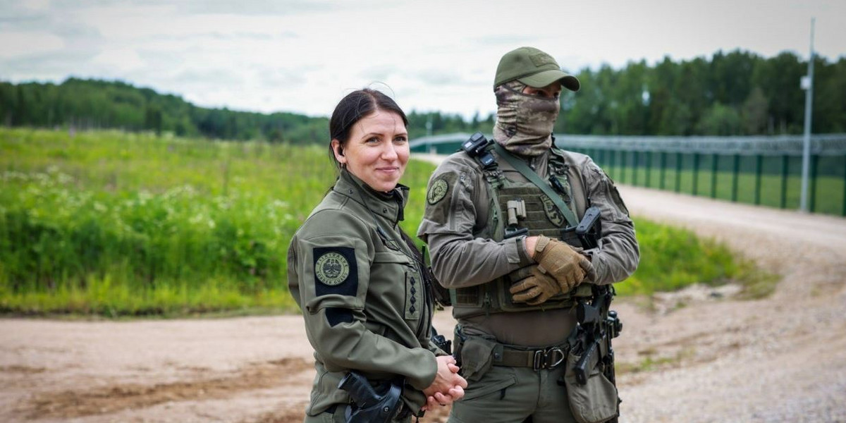 Funkcjonariusze estońskiej straży granicznej na tle nowego muru.