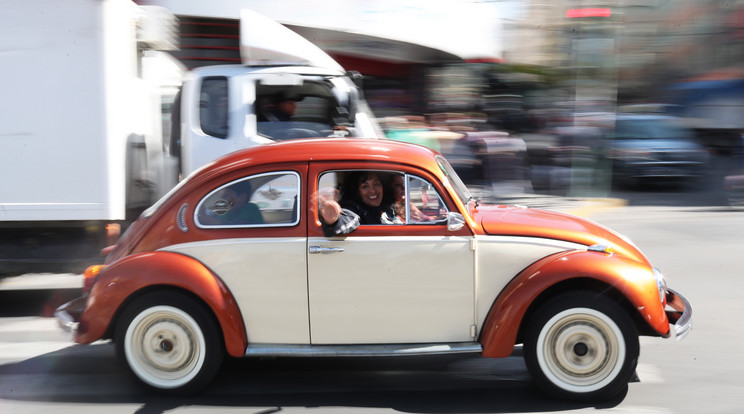 Egy nő integet a Volkswagen Bogarából