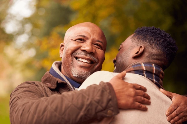 A elder man hugging another man